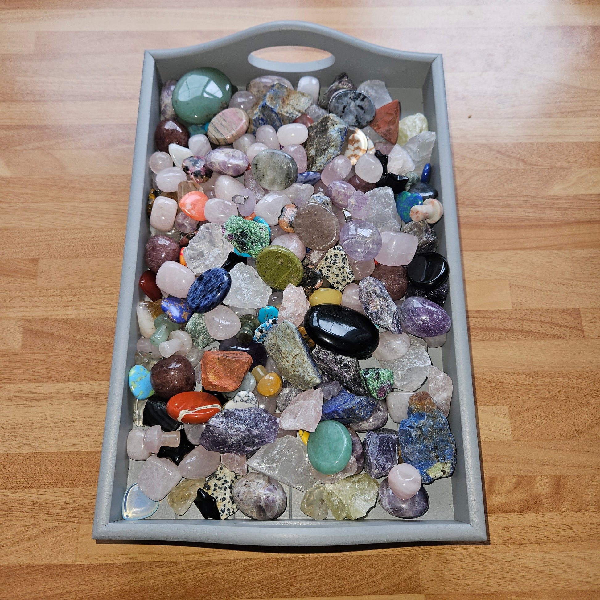 Gray tray filled with multicolored stones on a wooden surface
