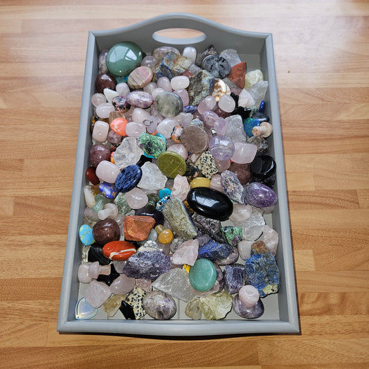 Gray tray filled with multicolored stones on a wooden surface